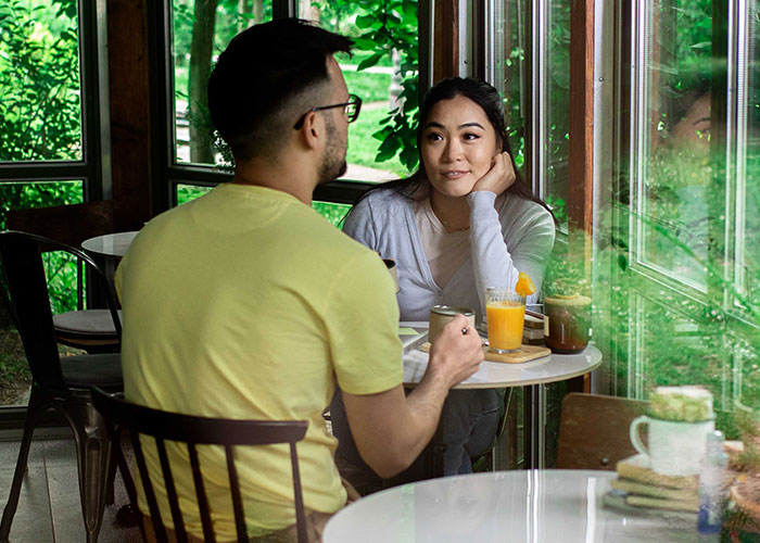 Woman and man having a conversation in a cafe, woman contemplating starting a new life in France after success challenges. Woman and man having a conversation in a cafe, woman contemplating starting a new life in France after success challenges.