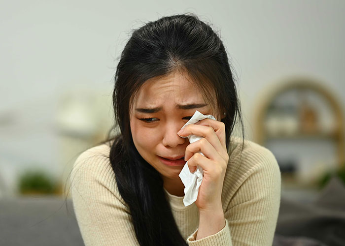 Woman crying and wiping tears, upset about leaving the US to start a new life in France after relationship struggles. Woman crying and wiping tears, upset about leaving the US to start a new life in France after relationship struggles.