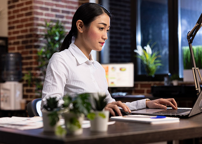 Woman working focused on laptop in modern office, starting new life abroad after success challenges in US. Woman working focused on laptop in modern office, starting new life abroad after success challenges in US.