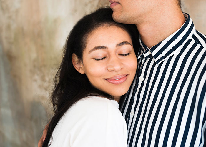 Woman smiling with eyes closed while hugging man in striped shirt, symbolizing woman success and new life in France. Woman smiling with eyes closed while hugging man in striped shirt, symbolizing woman success and new life in France.