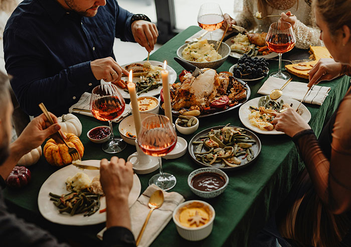 Family gathered around a festive dinner table, sharing a meal with candles and wine, tense atmosphere linked to bride mad cousin dress wedding.