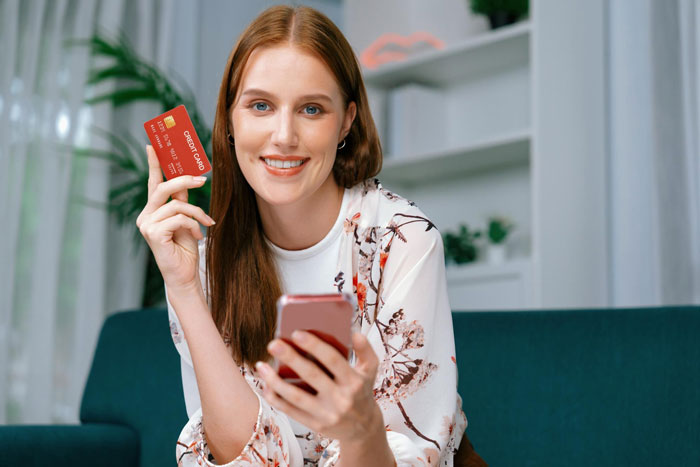 Young woman holding a credit card and smartphone, illustrating brother uses sister’s credit card without permission issue. Young woman holding a credit card and smartphone, illustrating brother uses sister’s credit card without permission issue.