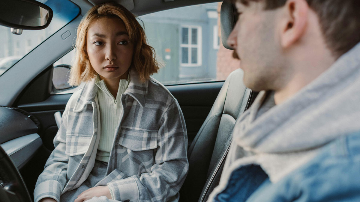 Couple sitting in a car having a tense conversation, illustrating chaotic and dramatic breakup stories.