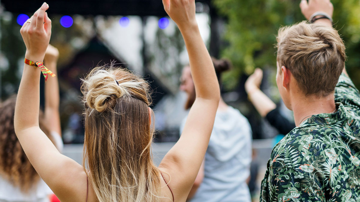 Young people raising hands enjoying an outdoor event, representing unexpected stories of a bad day turning life-changing.