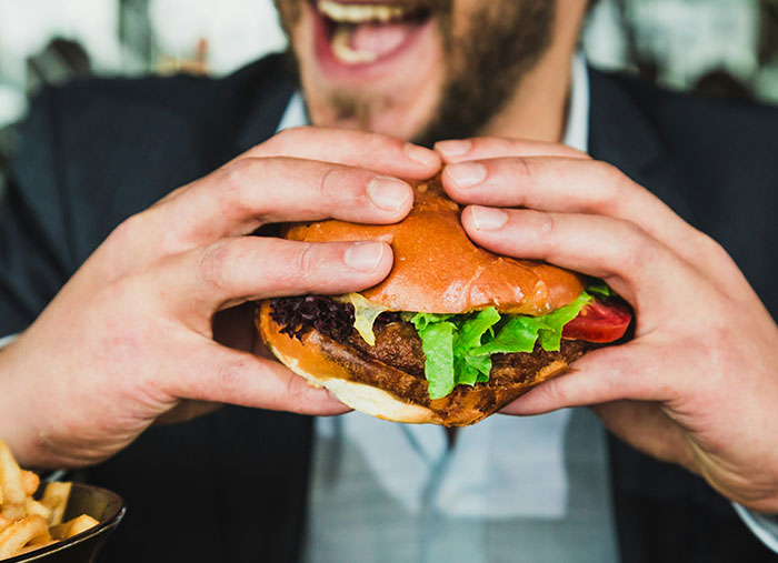 Man holding and about to eat a hamburger, illustrating unexpected stories showing how a bad day turned into a life-changing one.