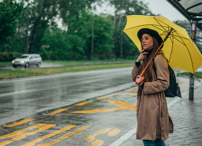 Young woman holding a yellow umbrella on a rainy day, illustrating unexpected stories of how a bad day turned life-changing.