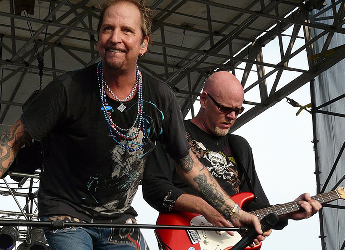 Two musicians playing guitar and singing on stage during a live concert, capturing unexpected stories and moments.