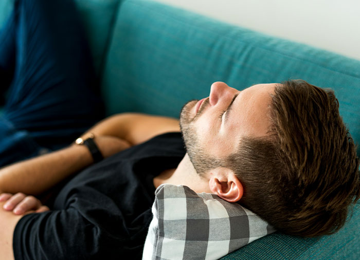 Young man resting on teal couch with checked pillow, illustrating unexpected stories of a bad day turning life-changing.