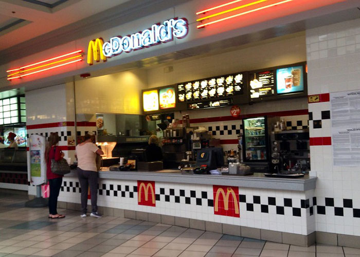 McDonald's fast food counter inside a mall with customers placing orders, illustrating businesses that lost clients.
