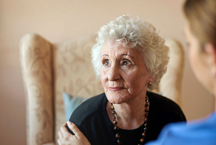 Elderly woman with white hair sitting thoughtful, representing a lady telling grandkid about a bull and nose ring.