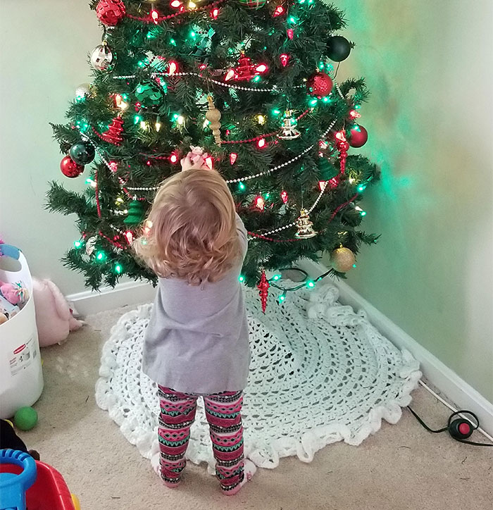 Young child decorating a Christmas tree representing a father unable to afford Christmas expenses this holiday season.