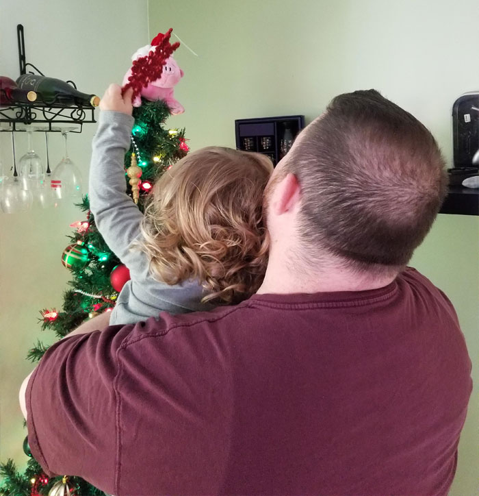 Father and child decorating a Christmas tree, reflecting the father’s struggle with affording Christmas this year.