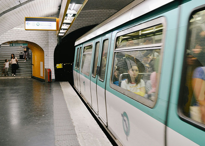 Passengers inside a crowded subway train at a station platform, capturing a chaotic urban commute scene.