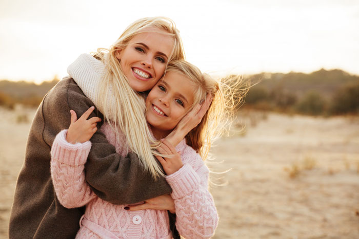 Mother and daughter smiling and hugging outdoors, highlighting the significance of mom’s native language despite dad’s ban. Mother and daughter smiling and hugging outdoors, highlighting the significance of mom’s native language despite dad’s ban.