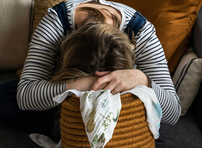 Woman with head down over basket, reflecting on choosing nose job over kids college funds decision. Woman with head down over basket, reflecting on choosing nose job over kids college funds decision.