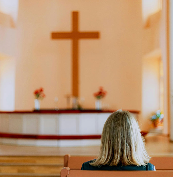 Woman sitting in a US megachurch pew facing a large wooden cross during a social experiment sparking online frenzy. Woman sitting in a US megachurch pew facing a large wooden cross during a social experiment sparking online frenzy.