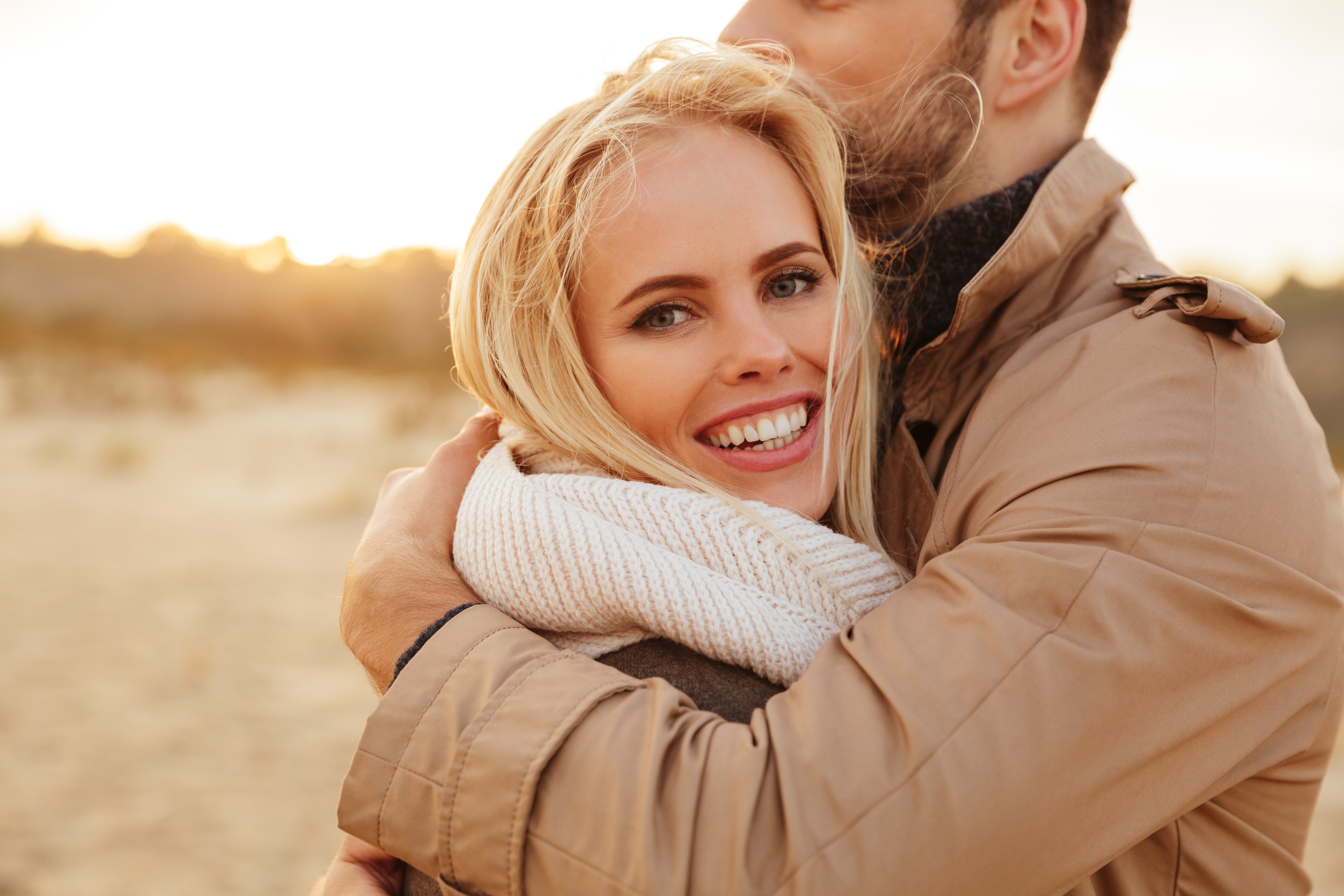 Smiling bride wrapped in a cozy scarf embraces groom outdoors at sunset, reflecting wedding and controlling MIL themes. Smiling bride wrapped in a cozy scarf embraces groom outdoors at sunset, reflecting wedding and controlling MIL themes.