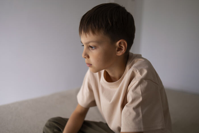 Young boy with a serious expression sitting indoors, reflecting on a real-life horror story moment.