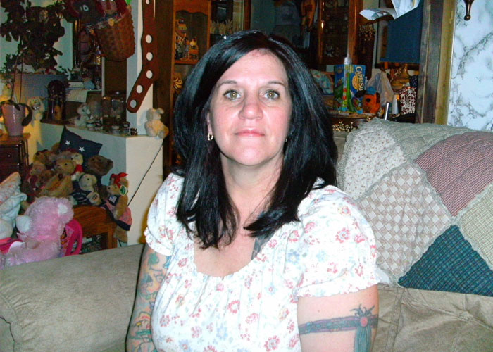 Woman with dark hair sitting on a couch in a room filled with stuffed animals and home decor, related to missing woman’s body case.