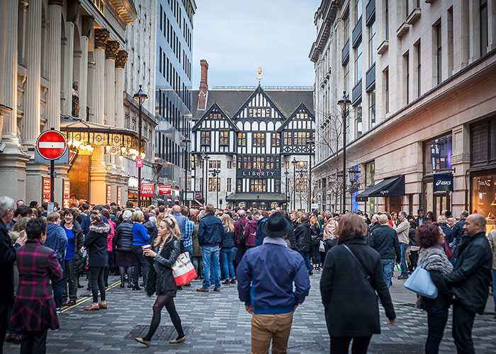 Crowded European street with people walking and shopping, illustrating life in Europe compared to the USA debate.