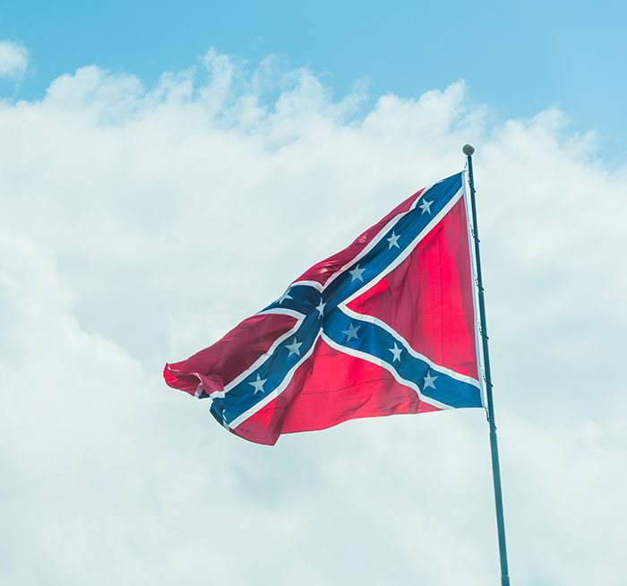 Confederate flag waving against the sky symbolizing controversy over racist name change and bullying at school. Confederate flag waving against the sky symbolizing controversy over racist name change and bullying at school.