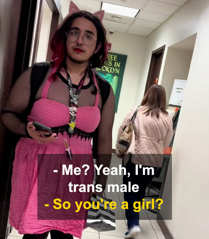 Bearded trans man in pink dress standing in hallway with a woman walking away in a restroom debate setting. Bearded trans man in pink dress standing in hallway with a woman walking away in a restroom debate setting.