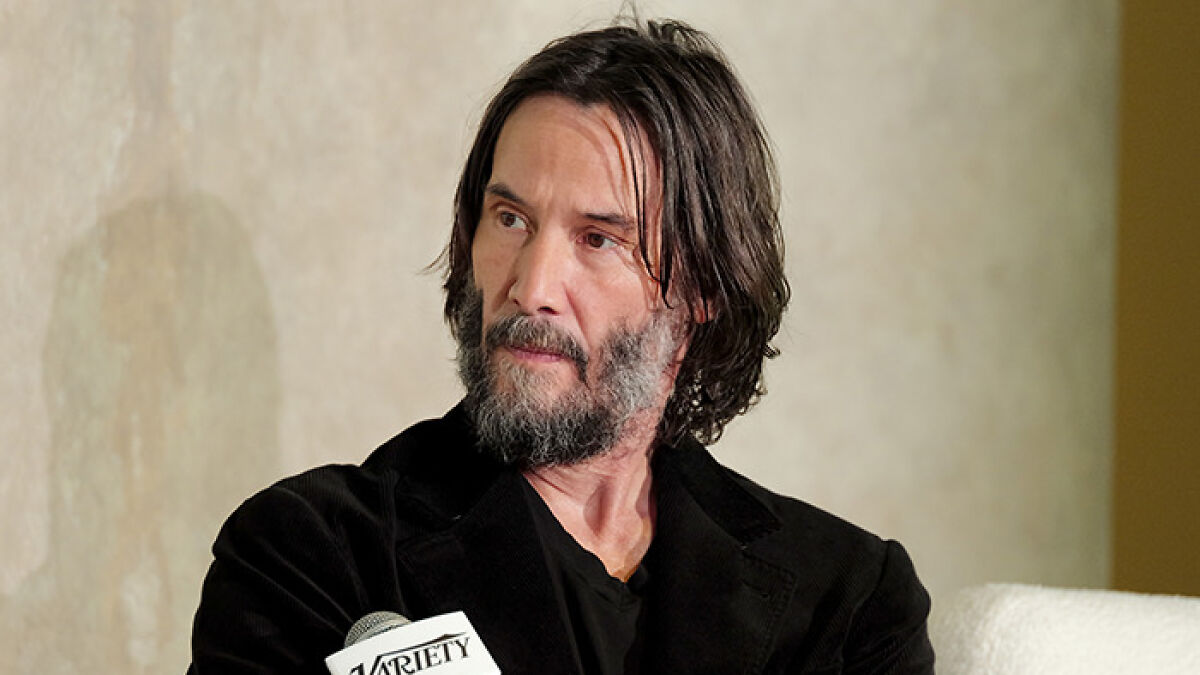 Actor with beard and long hair speaking at a panel, sharing celebrity confessions about movies years after filming.