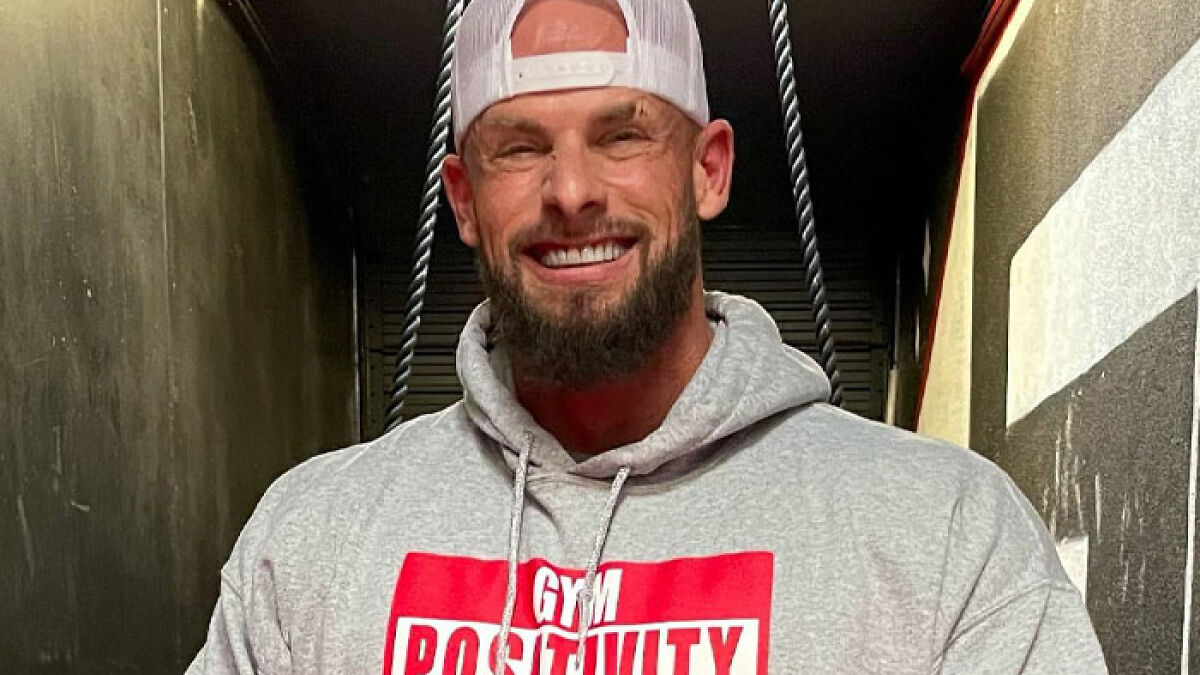 Joey Swoll smiling in a white cap and hoodie, weighing in on Gold's Gym trans locker controversy debate.