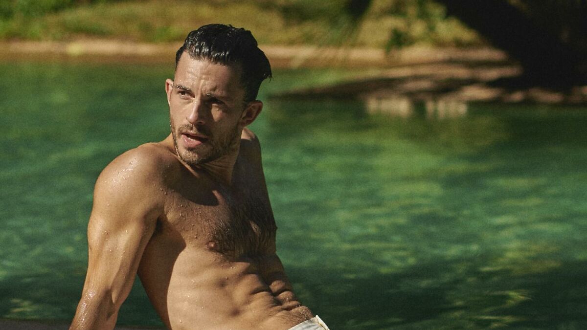 Man with wet hair and toned physique relaxing by the pool, representing sexiest man alive winners and their appeal.