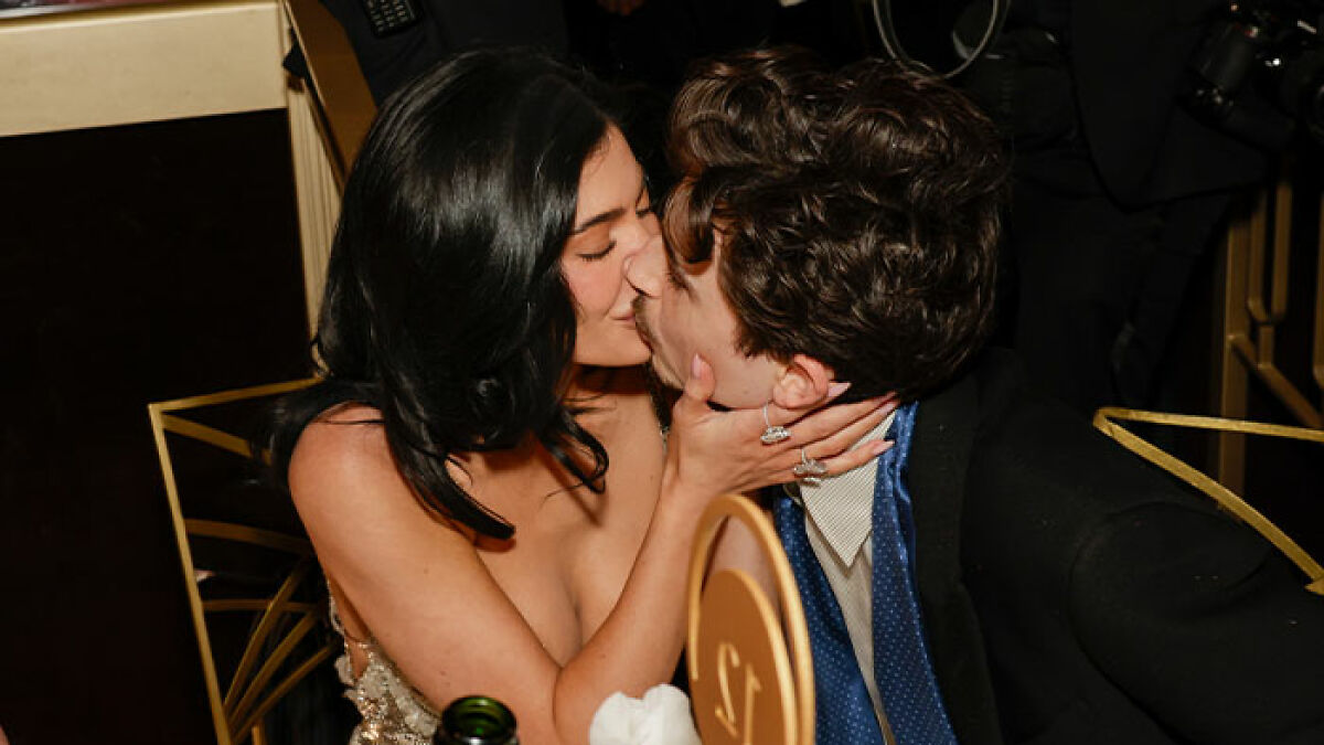 Timothu00e9e Chalamet and companion sharing a kiss at an event amid backlash over his comments about having kids