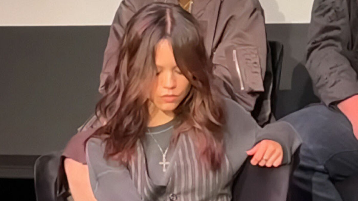 Jenna Ortega looking down with a silent expression during the Wednesday cast event, raising concern over her behavior.