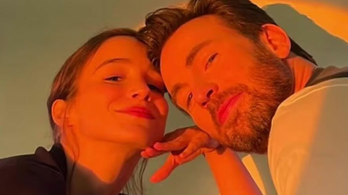 Chris Evans and a woman posing closely together, with warm lighting highlighting their faces in an intimate moment.