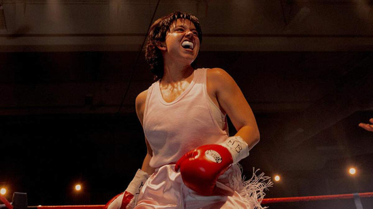 Plus-size model wearing boxing gloves inside ring, showing fierce expression during intense fight scene.