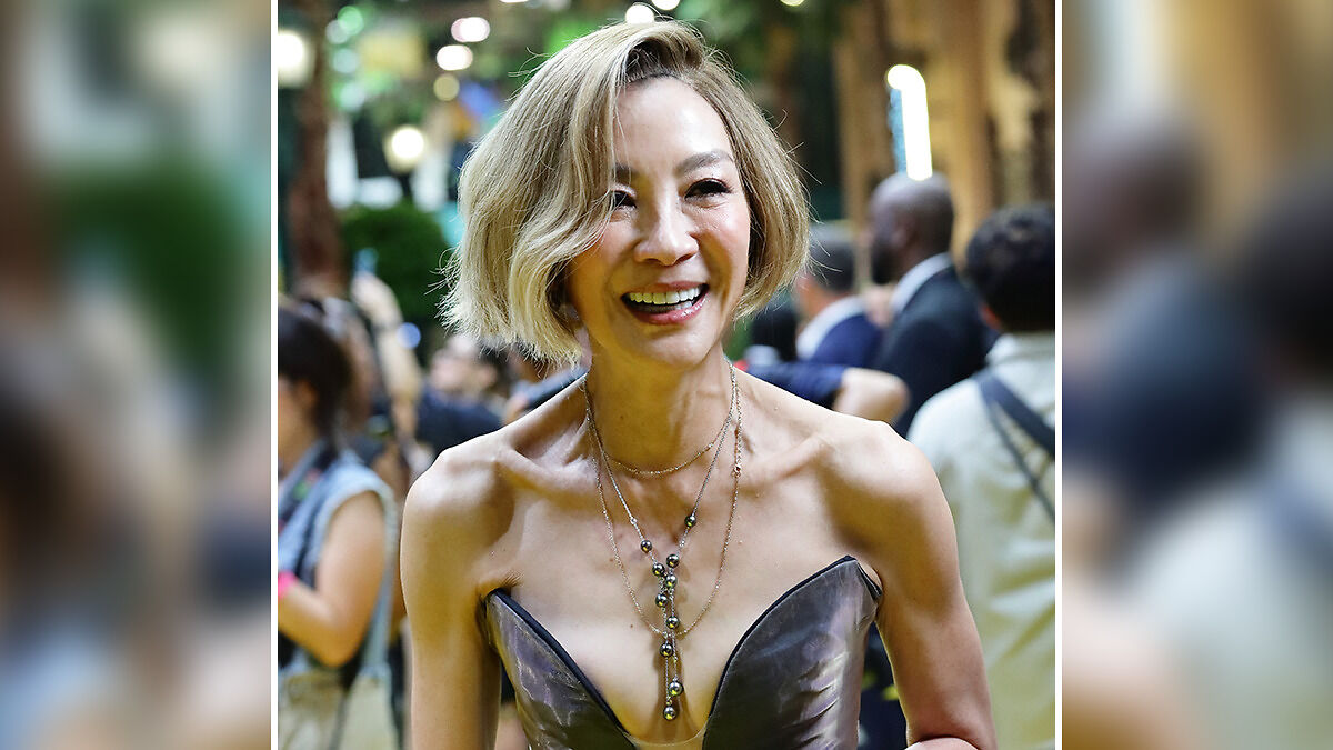 Michelle Yeoh looking extremely thin with visible collarbones and shoulder muscles at a public event, smiling brightly.