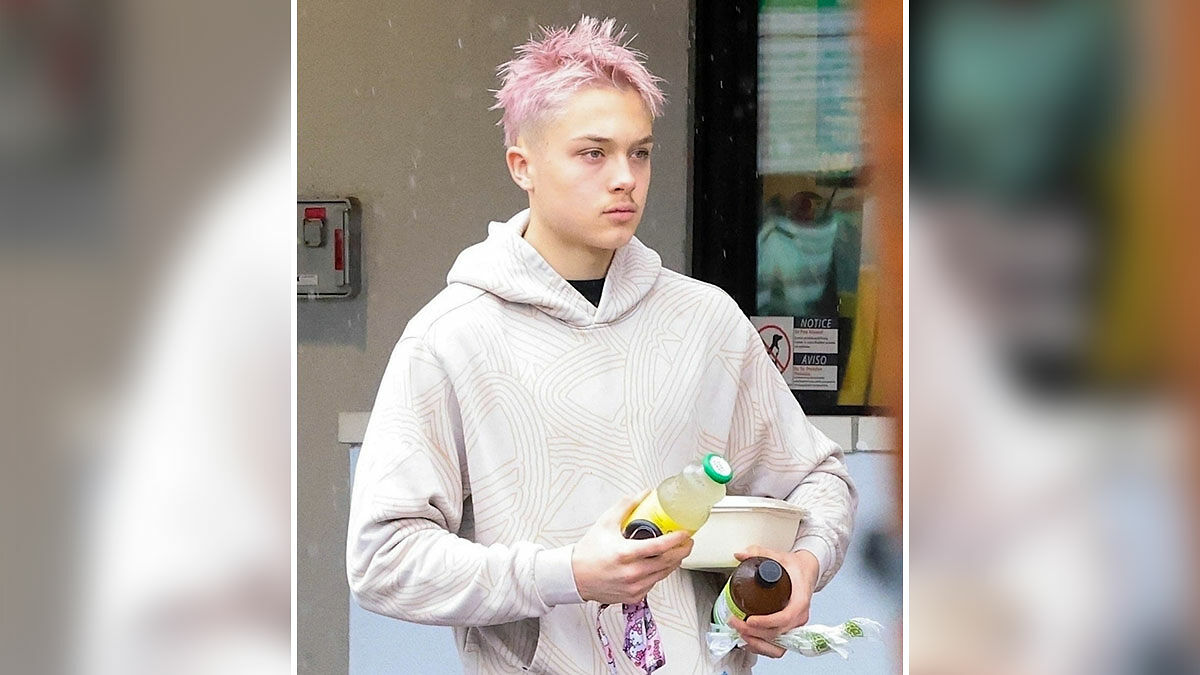 Knox, Angelina Jolie and Brad Pitt's son, with pink dyed hair, wearing a beige hoodie and holding drinks and food containers.