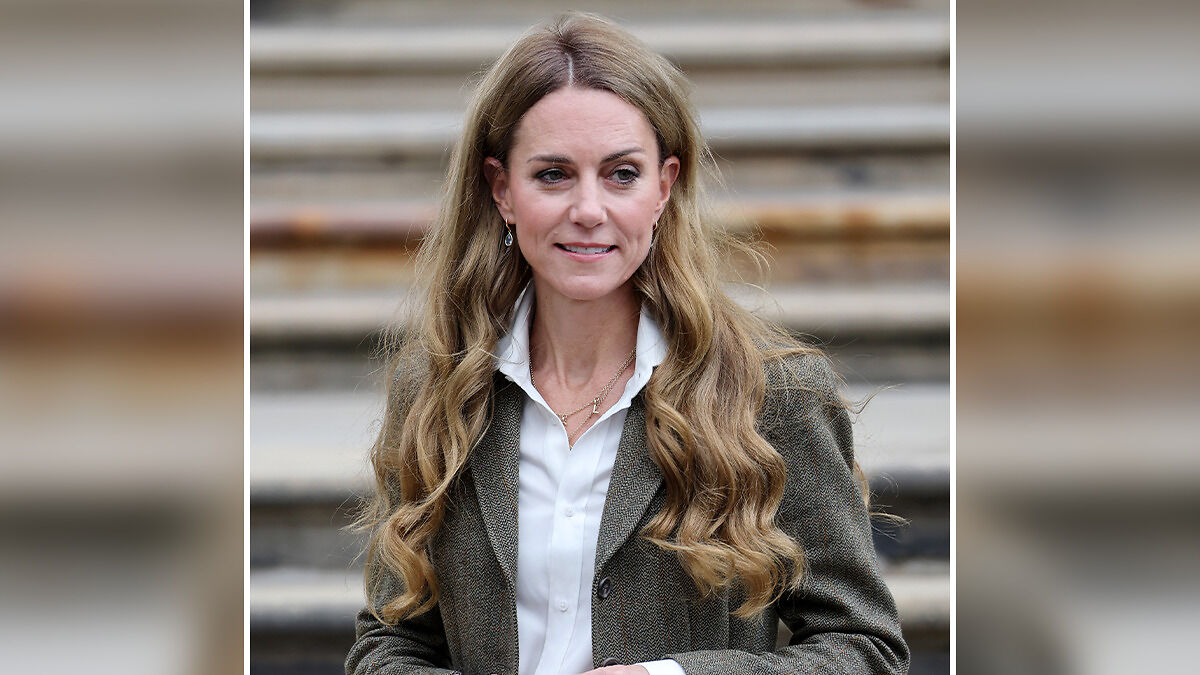 Kate Middleton with long blonde hair styled in loose waves, wearing a blazer and white shirt outdoors by stone steps.
