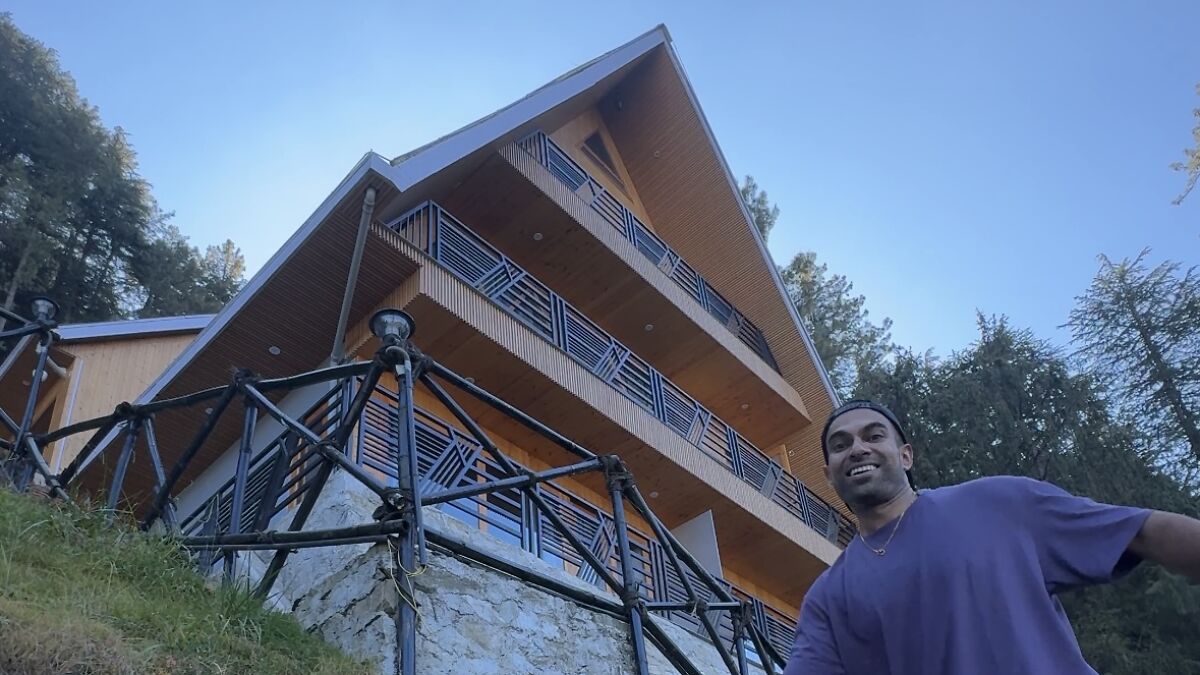 Man smiling near wooden balcony of modern house surrounded by forest during Kasauli escape trip