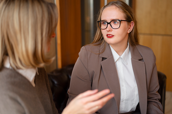 Two female employees in an office having a tense conversation during a frustrating office swap situation. Two female employees in an office having a tense conversation during a frustrating office swap situation.