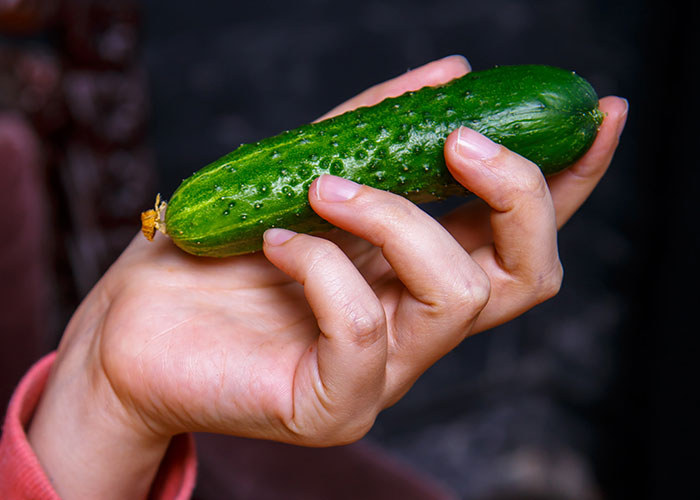 Hand holding a fresh green cucumber, illustrating one of the weirdest and craziest ER stories involving unusual objects.