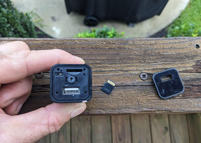 Hand holding a small hidden camera with its memory card removed, illustrating disturbing online content related to narrowly avoided kidnapping.