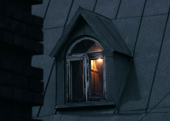 Dimly lit window at night on an old building, evoking a sense of fear and narrowly avoided kidnapping danger.