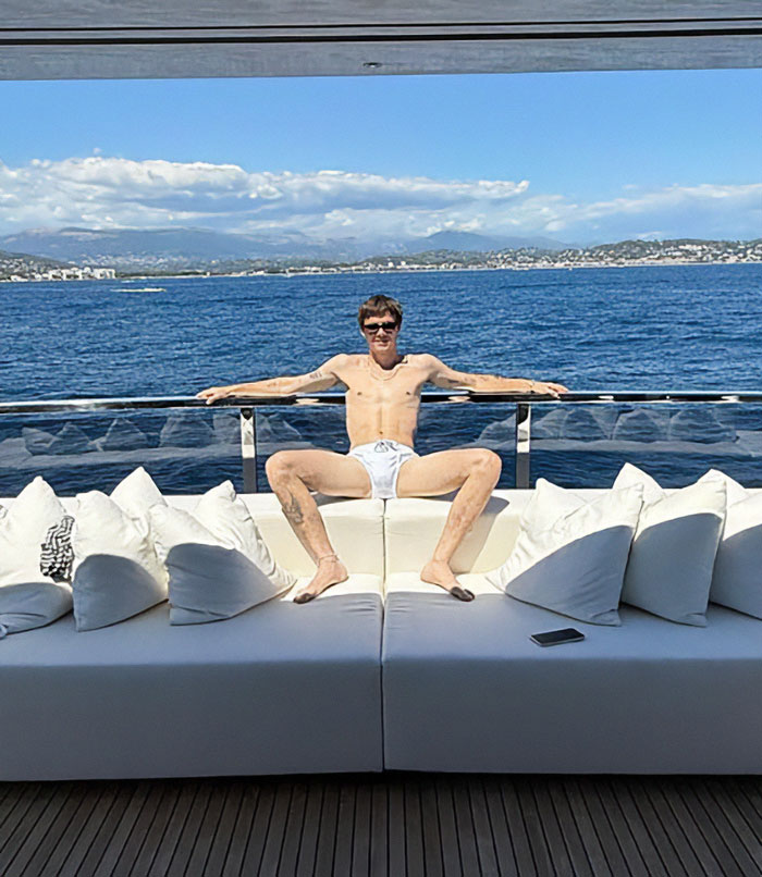 Celebrity in white swimwear relaxing on a yacht deck with ocean view, revealing more than they should in 2025 frenzy.