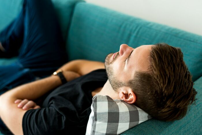 Man resting with eyes closed on couch, reflecting on uniquely awkward weddings that crashed and burned before starting.