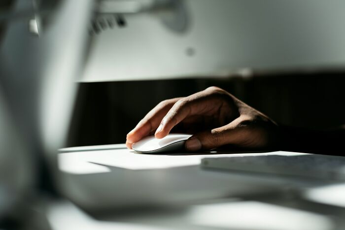 Hand of a worker using a computer mouse in an office setting, highlighting workers share unprofessional things done.