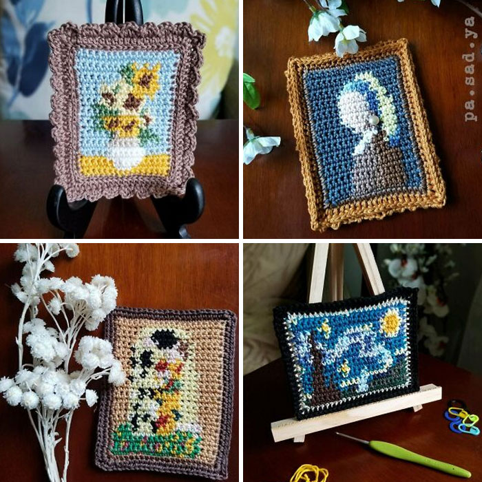 Four miniature framed crochet artworks displayed on stands and next to flowers, showcasing detailed crochet projects by enthusiasts.