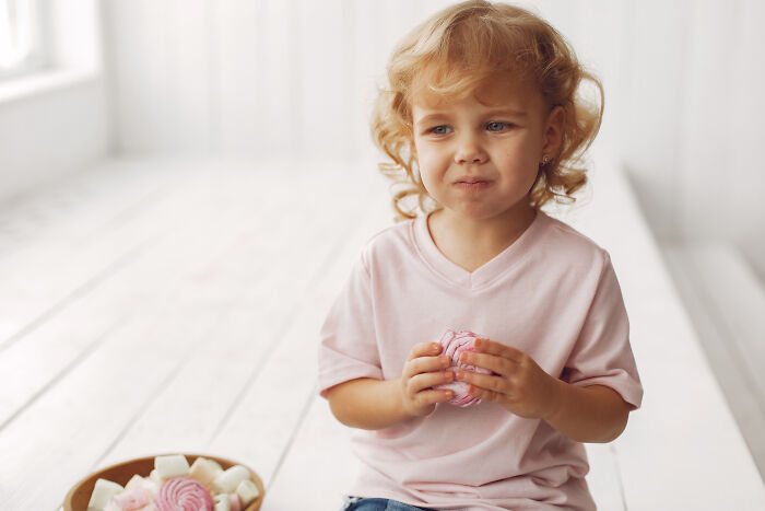 Toddler with curly hair holding a treat, capturing daily screaming and meltdowns that take a toll on family life.