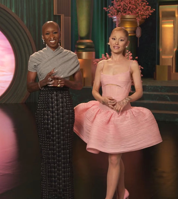 Two women stand in a colorful setting during a press event highlighting Ariana Grande revealing diagnosis amid Wicked tour. Two women stand in a colorful setting during a press event highlighting Ariana Grande revealing diagnosis amid Wicked tour.