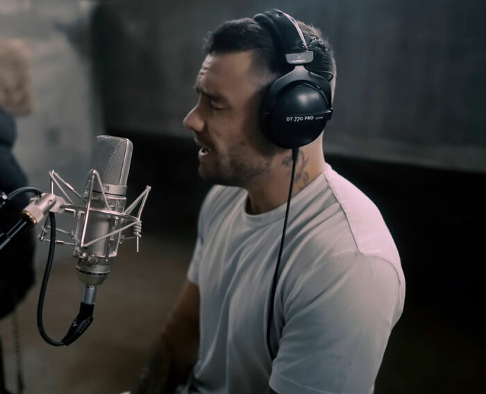 Man wearing headphones and white shirt speaking into a microphone, relating to Simon Cowell and Liam Payne mental health. Man wearing headphones and white shirt speaking into a microphone, relating to Simon Cowell and Liam Payne mental health.