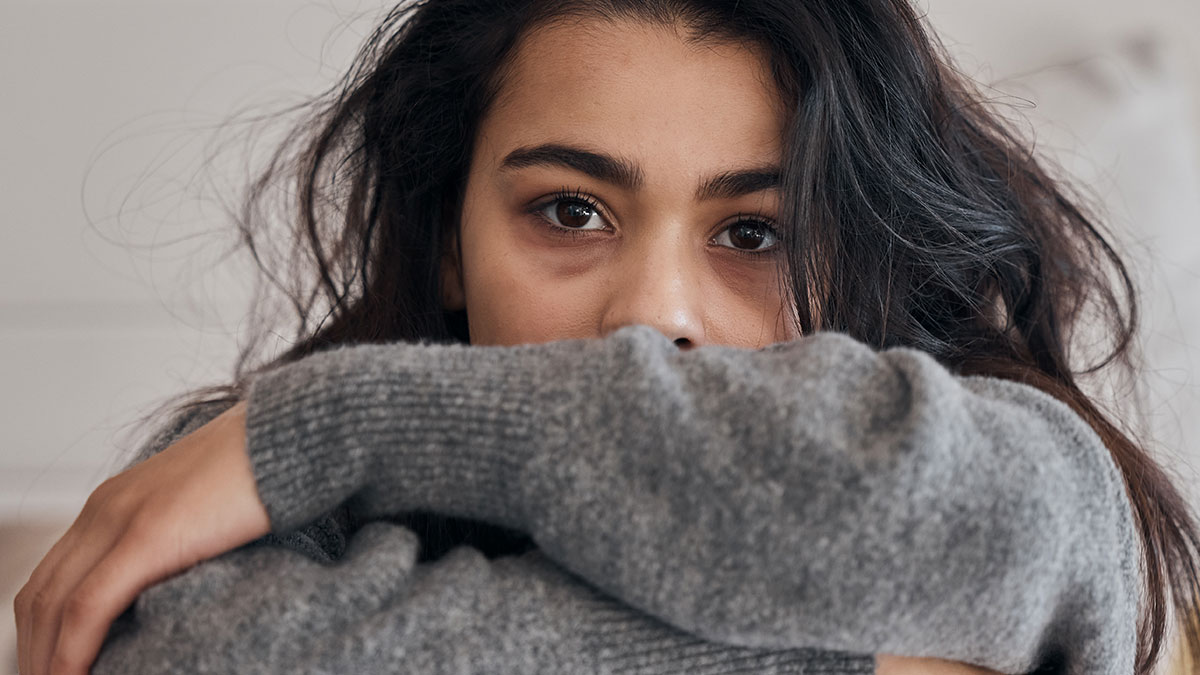 Teen girl with sad expression resting arms on knees, reflecting feelings related to adoption and family struggles.