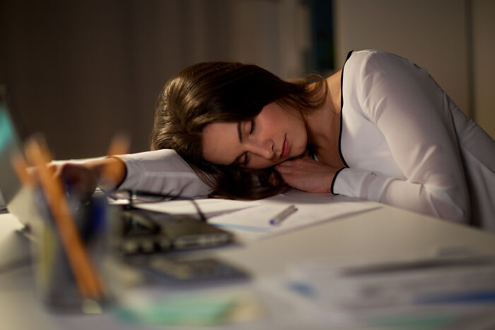 Woman sleeping at desk surrounded by papers and calculator, highlighting the powerful impact of water.